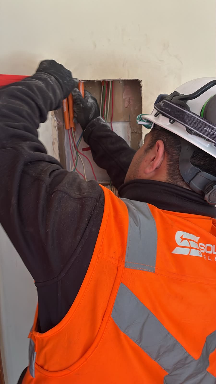 Técnico eléctrico instalando cableado en muro